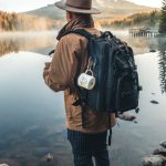 Travel Photography - Man in Brown Jacket and Brown Hat Standing on Rock Near Lake